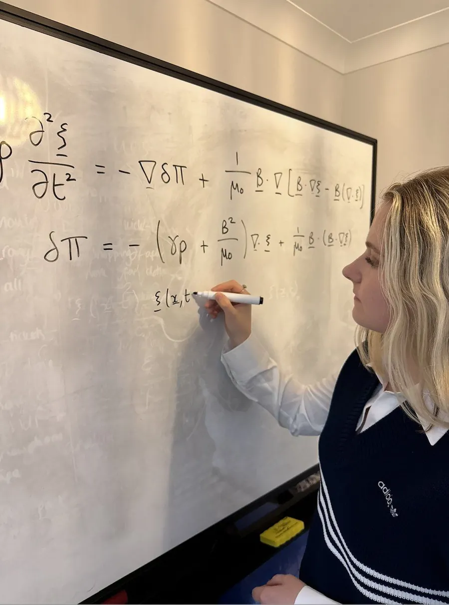 A student writing a differential equation on a lecture whiteboard